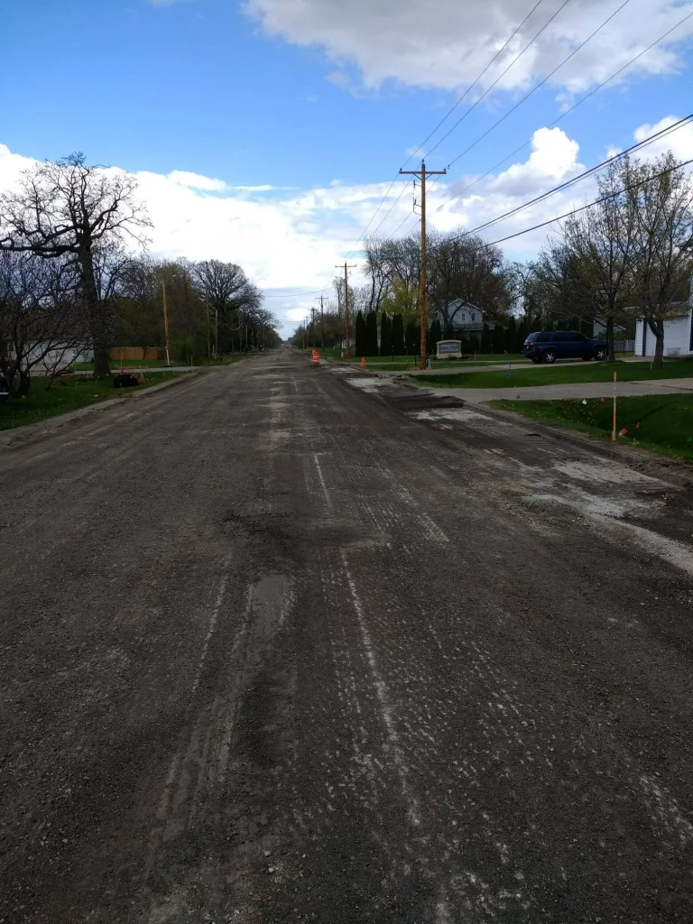 Long dirt road in residential area with electric pole