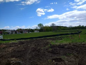 Sectioned off grass surrounded by dirt and houses in the background