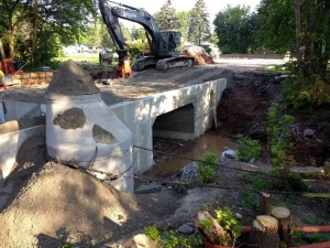 An excavator works on top of a small bridge