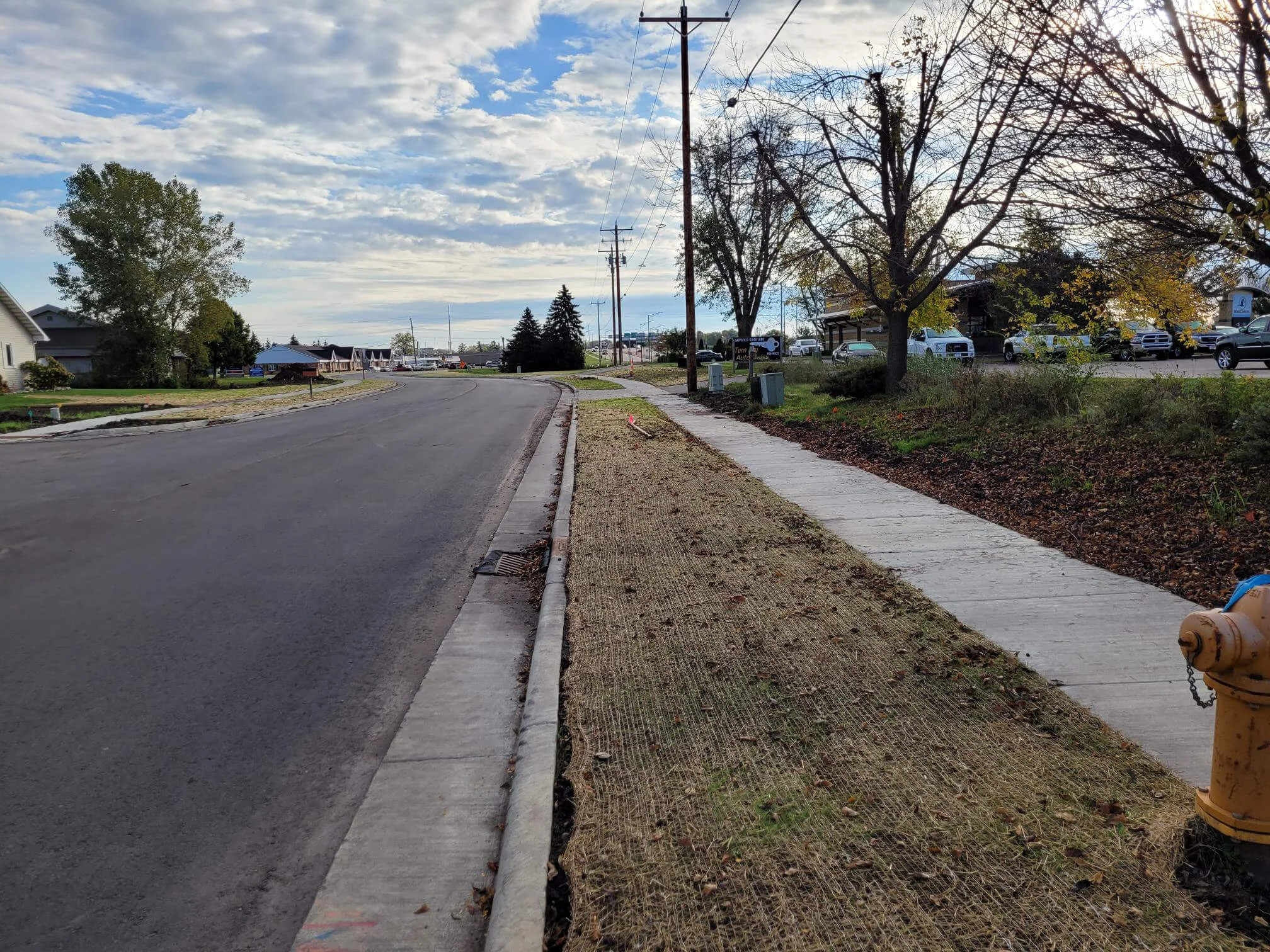 Landscaping work is completed between the sidewalk and road on a small road in the Town of Algoma